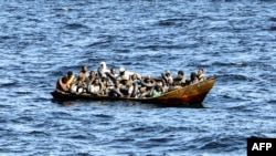 АРХИВА - Мигрантите од африканско потекло на мал брод додека туниската крајбрежна стража се подготвува да ги префрли на нивниот брод, на море меѓу Тунис и Италија, 10 август 2023 година.