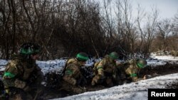 Ukrainian servicemen take cover during a shelling outside the frontline town of Bakhmut, amid Russia's attack on Ukraine, in Donetsk region, Ukraine, Feb. 13, 2023. 