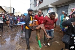 FILE - Residents rescue a woman who was caught during heavy rain in the Mathare area of Nairobi, Kenya, April 24, 2024. (AP Photo/Andrew Kasuku, File)