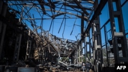Locals examine the remains of an industrial building that has been hit by a Russian missile, in Odesa, May 18, 2023, amid Russia's continued invasion of Ukraine.
