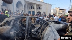 据两名巴勒斯坦消息人士称，2024年8月21日的黎巴嫩，在以色列袭击南部港口城市西顿郊区后，人们和黎巴嫩军人站在一辆被烧毁的汽车附近。(路透社照片)