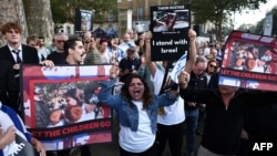 民眾手舉被巴勒斯坦武裝份子劫為人質的以色列婦女和兒童的照片在倫敦的英國首相官邸唐寧街10號外舉行集會。（2023年10月9日）