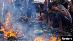 Палестинци бараат храна меѓу изгорените остатоци како последица на израелски напад врз област наменета за раселените луѓе во Рафа во јужниот дел на појасот Газа, 27 мај 2024 година