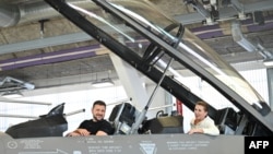 Ukrainian President Volodymyr Zelenskyy, left, and Danish Prime Minister Mette Frederiksen sit in a F-16 fighter jet in the hangar of the Skrydstrup Airbase in Vojens, northern Denmark, on Aug. 20, 2023. 