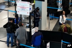 FILE - A sign warns travelers not to bring guns through the Transportation Security Administration checkpoint at O'Hare International Airport in Chicago, Dec. 19, 2022.