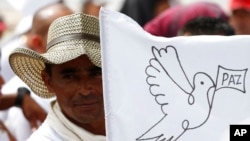 ARCHIVO - En esta fotografía del 27 de junio de 2017, un rebelde de las Fuerzas Armadas Revolucionarias de Colombia, FARC, ondea una bandera blanca de la paz durante un acto para conmemorar la finalización de su proceso de desarme en Buenavista, Colombia. [ (AP/Fernando Vergara]
