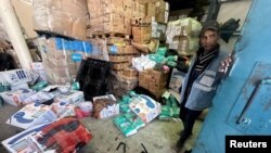 Seorang pekerja Palestina berdiri di samping kotak bantuan yang berlumuran darah, di pusat distribusi bantuan UNRWA usai serangan Israel di Rafah, Jalur Gaza selatan, 13 Maret 2024.