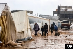Warga Palestina berjalan di bawah hujan di sebuah kamp pengungsi di Rafah, di Jalur Gaza selatan tempat sebagian besar warga sipil mengungsi, 13 Desember 2023. (Foto: AFP)