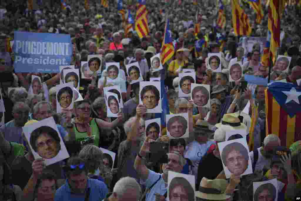 Supporters of Catalan independence leader Carles Puigdemont hold his portrait as they wait for his arrival near the Catalan parliament to to allegedly attend the investiture debate in Barcelona, Spain.