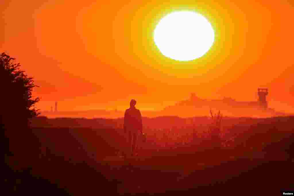 A migrant walks back to his makeshift camp at sunrise after a failed attempt to cross the Channel to the UK on a small boat, in Sangatte, near Calais, France.