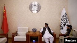 2023年10月19日，塔利班代理商務部長阿齊齊在阿富汗駐中國北京大使館接受路透社採訪時坐在阿富汗伊斯蘭酋長國和中國國旗中間。（路透社照片）
