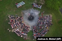 Para peserta dan pemandu duduk di sekitar lingkaran api unggun, Kamis, 20 Juni 2024, di YMCA Camp Kern di Oregonia, Ohio, saat gelombang panas pertama musim panas melanda AS. (Foto: AP/Joshua A. Bickel)