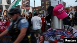 Demonstrators walk past a stall selling merchandise in support of Democratic presidential candidate and US Vice President Kamala Harris on the sidelines of the Democratic National Convention (DNC) in Chicago, Illinois, Aug. 22, 2024. 