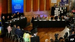 ARCHIVO - Excomandantes de las FARC, arriba a la derecha, asisten a una audiencia ante la Jurisdicción Especial para la Paz sobre secuestros durante el conflicto interno de Colombia en Bogotá, Colombia, el miércoles 22 de junio de 2022.