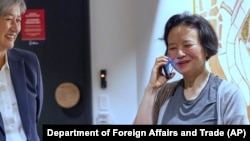 Chinese Australian journalist Cheng Lei, right, talks on the phone as Australia's Minister for Foreign Affairs, Penny Wong, watches at Tullamarine Airport in Melbourne, Oct. 11, 2023. 