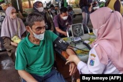 Seorang petugas kesehatan melakukan pemeriksaan kesehatan terhadap seorang pria sebelum memberikan vaksinasi COVID-19 di puskesmas di Jakarta, 1 Februari 2023. (Foto: Bay Ismoyo/AFP)