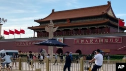 A security person watch over residents passing in front of Tiananmen Gate in Beijing, June 4, 2023.