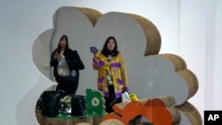 FILE - Women are reflected on a magic mirror as they shop at a fashion boutique in Beijing, Oct. 22, 2023.