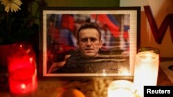 Sjumlah lilin ditempatkan di sekitar foto dari pemimpin oposisi Rusia, Alexey Navalny, dalam acara mengenang kematiannya di Trocadero, di dekat Menara Eiffel di Paris, Prancis, pada 19 Februari 2024. (Foto: Reuters/Benoit Tessier)