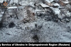 Warga berdiri di samping rumah tempat tinggal yang hancur di lokasi serangan rudal Rusia di Wilayah Dnipropetrovsk, Ukraina, 8 Januari 2024. (Foto: via Reuters)