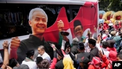 FILE - Para pendukung paslon capres-cawapres Pilpres 2024 Ganjar Pranowo dan Mohammad Mahfud, mengelilingi bus kampanye saat mendaftarkan diri di gedung Komisi Pemilihan Umum di Jakarta, 19 Oktober 2023. (AP/Achmad Ibrahim)