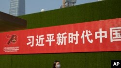 一名女子从北京街头张贴的一条宣传习近平新时代的标语下走过。（2019年9月27日）