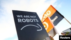 Transparent u rukama radnika Amazona na kom piše "Mi nismo roboti"