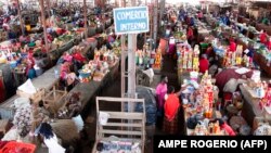 Pessoas fazem compras num mercado em Luanda, Angola. (Photo by AMPE ROGERIO / AFP)