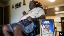 FILE — A portrait of American soldier Travis King is displayed near his grandfather, Carl Gates, in Kenosha, Wisconsin, July 19, 2023. Two days earlier, King dashed into North Korea while on a civilian tour of the Joint Security Area on the border between the two Koreas.  