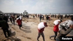 Wapalestina wakibeba magunia ya unga waliyopora kwenye lori la misaada