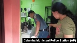 A policeman, left, inspects the area where a radio anchor was fatally shot by a man inside his home-based station in Calamba town in Misamis Occidenta province, southern Philippines, Nov. 5, 2023. 