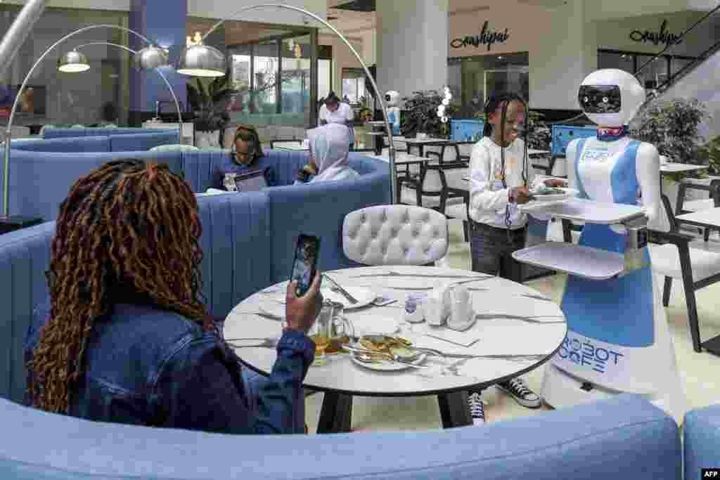A young patron retreives her meal order from a robotic waiter's tray at the Robot Cafe, Kenya's first restaurant to employ humanoid robots as waiters, in Nairob.