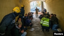 Rescued people, journalists and police officers take cover as an air-raid siren sounds during a Russian drone strike, in Kyiv, Ukraine, Oct. 17, 2022.