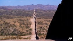 En esta foto del 19 de mayo de 2021, el muro fronterizo se extiende a lo largo del paisaje cerca de Sasabe, Arizona. Los cuerpos de un inusualmente alto número de migrantes que murieron en las zonas fronterizas de Arizona se está recuperando este verano.