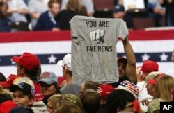 FILE - In this Oct. 4, 2018 file photo, a Trump supporter holds up a T-shirt reading "You Are Fake News" before a rally by President Donald Trump in Rochester, Minn. The Native American Journalists Association worries such rhetoric could impact free speech.