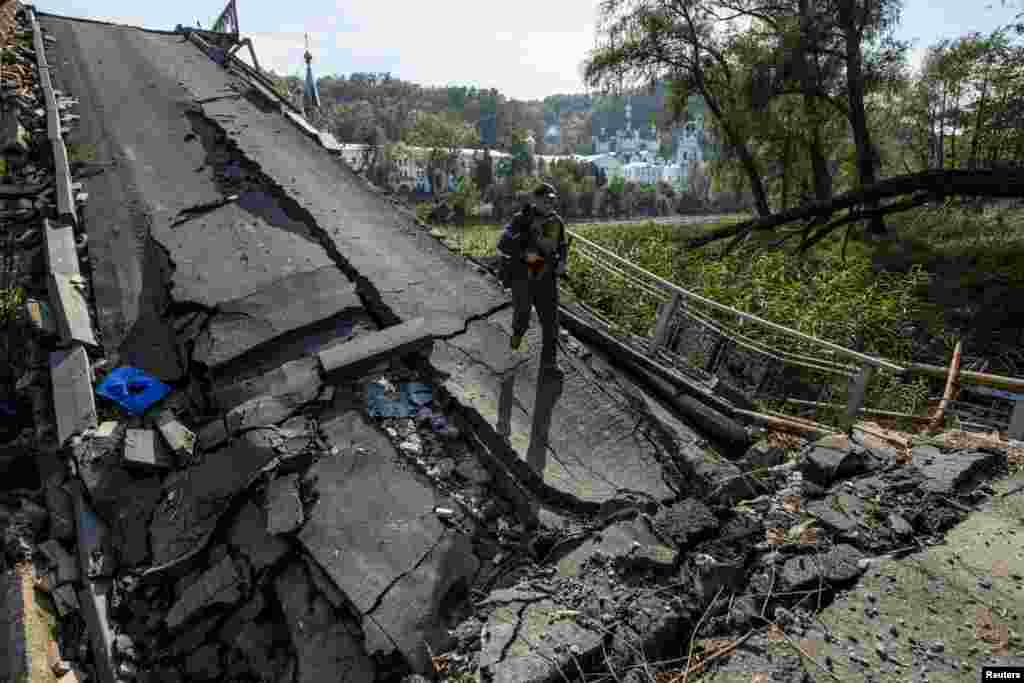 A service member of Ukraine's National Guard walks on a bridge over the Siverskyi Donets river destroyed during Russia's attack on Ukraine, in the town of Sviatohirsk, Donetsk region, Oct. 1, 2022.