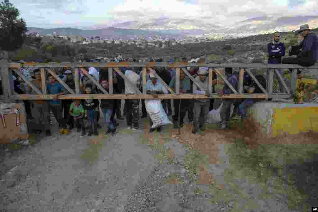 Palestinian farmers wait behind an Israeli army security gate to be allowed on to their lands to harvest olives, in the West Bank village of Salem, east of Nablus.