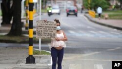 Migrante venezolana sostiene un cartel con un mensaje escrito a mano pidiendo comida o dinero en un cruce peatonal en Bogotá, Colombia, el 9 de febrero de 2021.