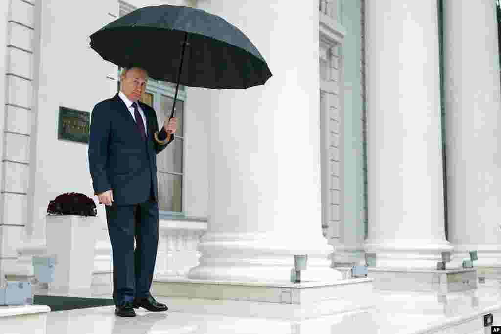 Russian President Vladimir Putin holds an umbrella as he waits for Armenian Prime Minister Nikol Pashinyan prior to their talks, at the Bocharov Ruchei residence in the Black Sea resort of Sochi, Russia. (Sergei Bobylev, Sputnik, Kremlin Pool Photo via AP)