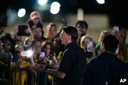 Brazilian President Jair Bolsonaro, who is running for another term, talks to followers after general election polls closed in Brasilia, Brazil, Sunday, Oct. 2, 2022. (AP Photo/Eraldo Peres)