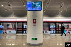 Seorang petugas mengenakan masker, berjalan di stasiun kereta bawah tanah yang lengang di sebelah resor Universal Studios Beijing, yang menurut pemberitahuan ditutup untuk pengendalian epidemi, di Beijing, Rabu, 26 Oktober 2022. (AP/Mark Schiefelbein)