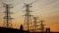 FILE - Locals walk past electricity pylons in Soweto, South Africa, July 3, 2022. Matshela Koko, the former head of the country's power provider Eskom has been charged with multiple counts related to corruption, fraud and money laundering.