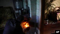 Viktor Palyanitsa akiwasha moto kwa ajili ya kupata joto nyumbani kwake Kurylivka, Ukraine, Oct. 16, 2022