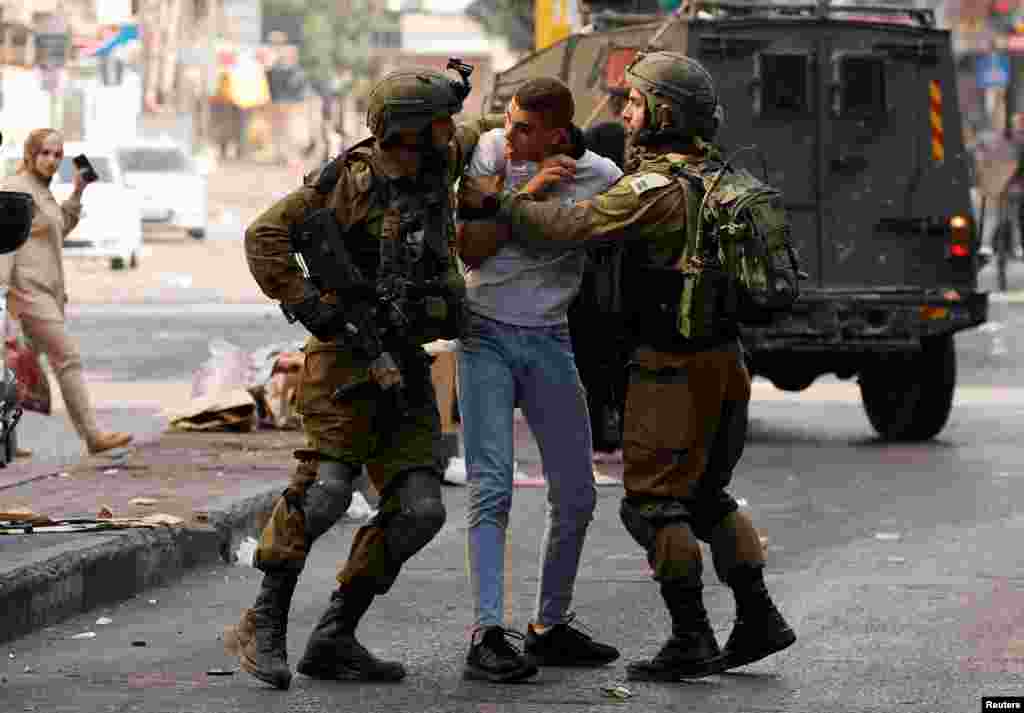 Members of the Israeli forces detain a Palestinian man amid clashes, in Hebron, in the Israeli-occupied West Bank.