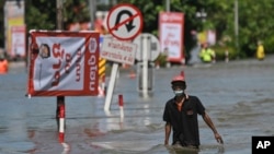 A resident wades through floodwaters, Wednesday, Oct. 5, 2022, in Ubon Ratchathani province, northeastern Thailand.