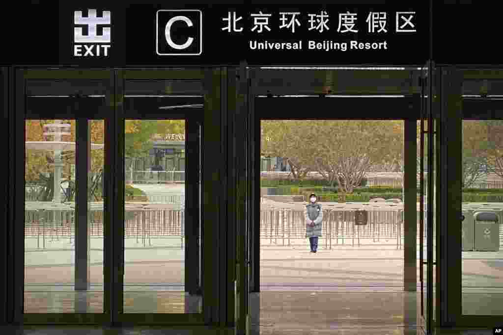 A worker wearing a face mask stands outside a subway station exit to stop visitors from going to the Universal Studios Beijing resort, which was closed for pandemic control, in Beijing, China.
