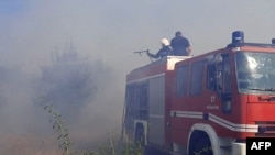 This handout picture released by Ukraine Emergency Service on July 17, 2022 shows firefighters puting out a fire on a wheat field burned as a result of shelling in Mykolaiv region. (Photo by Ukraine Emergency Service/AFP)