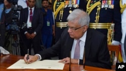 In this photo provided by the Sri Lankan President's Office, newly elected president Ranil Wickremesinghe, signs a document after taking the oath of office, in Colombo, Sri Lanka, July 21, 2022.