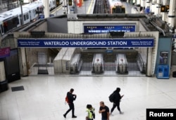 Orang-orang berjalan melewati gerbang tertutup di pintu masuk stasiun Bawah Tanah Waterloo, London, Inggris, saat para pekerja di Kereta Bawah Tanah London melancarkan aksi mogok, 19 Agustus 2022. REUTERS/Henry Nicholls