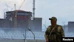 FILE - A serviceman with a Russian flag on his uniform stands guard near the Zaporizhzhia nuclear power plant in the course of Ukraine-Russia conflict outside the Russian-controlled city of Enerhodar in the Zaporizhzhia region, Ukraine, Aug. 4, 2022. 